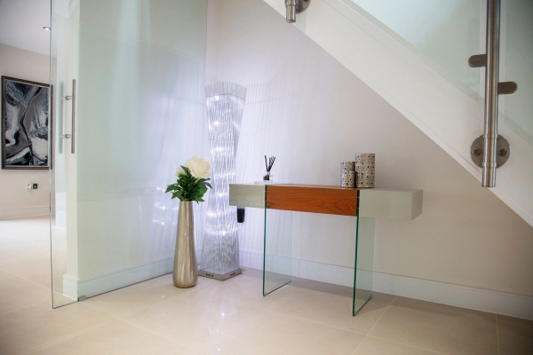 Minimalist entrance hall featuring a floating glass console table and a decorative illuminated column light, Love Locations GU5.