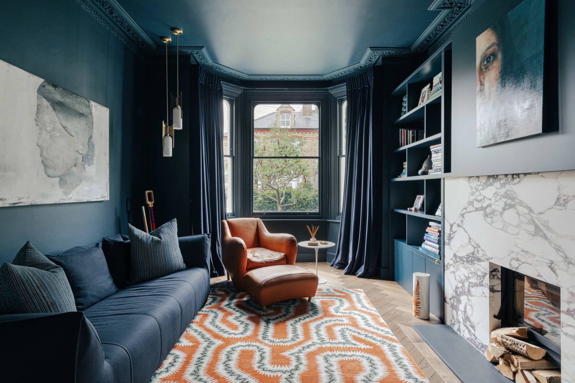 Deep blue television snug with bay window seating, dark curtains, and an orange patterned rug, ideal for luxury brand advertising, Love Locations.