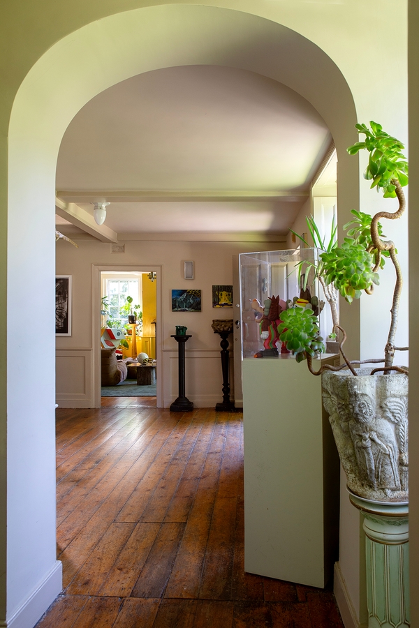 Hallway entrance looking past indoor plants toward a vibrant yellow living room, Love Locations ME13.