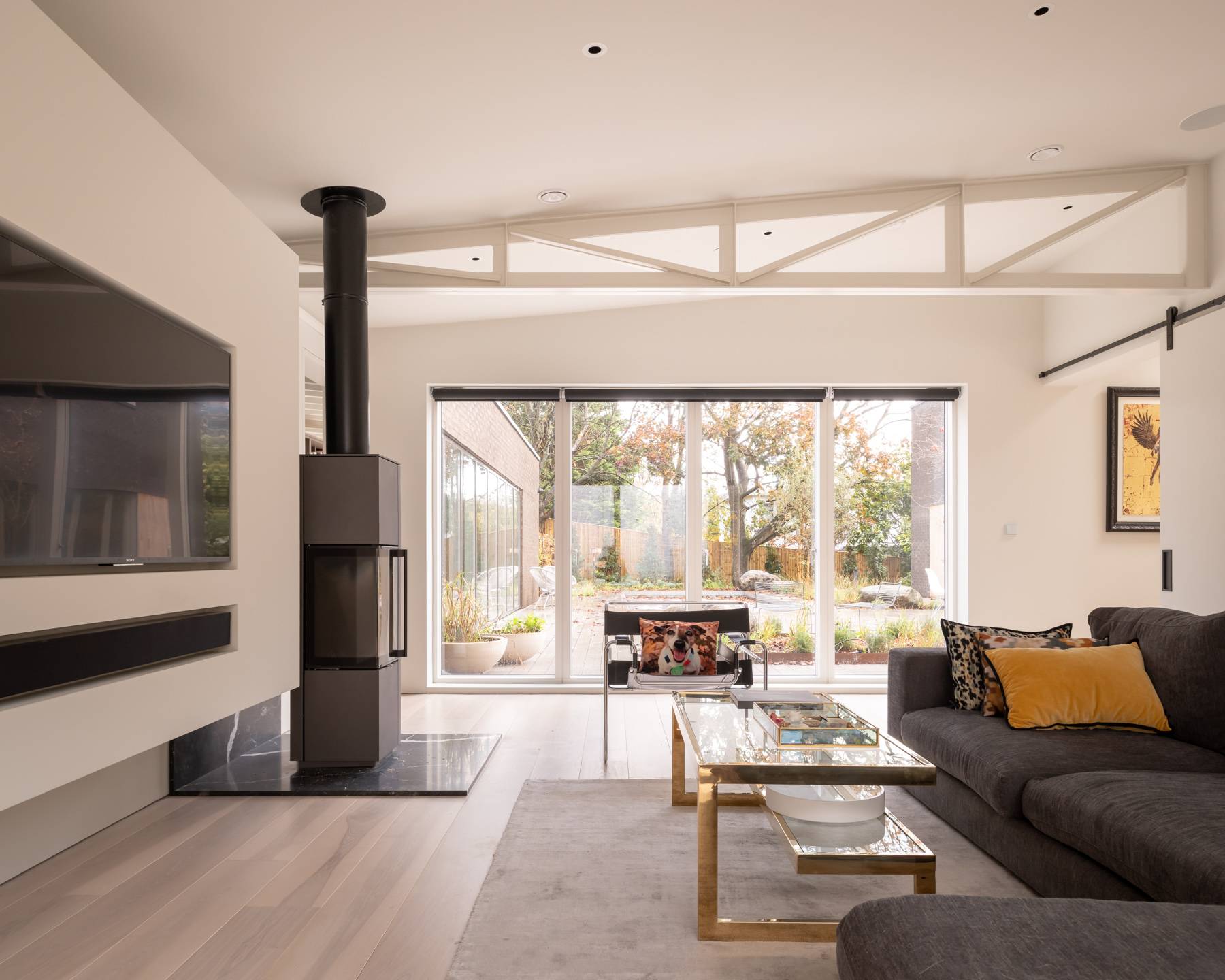 Lounge room featuring a modern black log-burning stove, grey corner sofa, and floor-to-ceiling glass patio doors, Love Locations BN3.