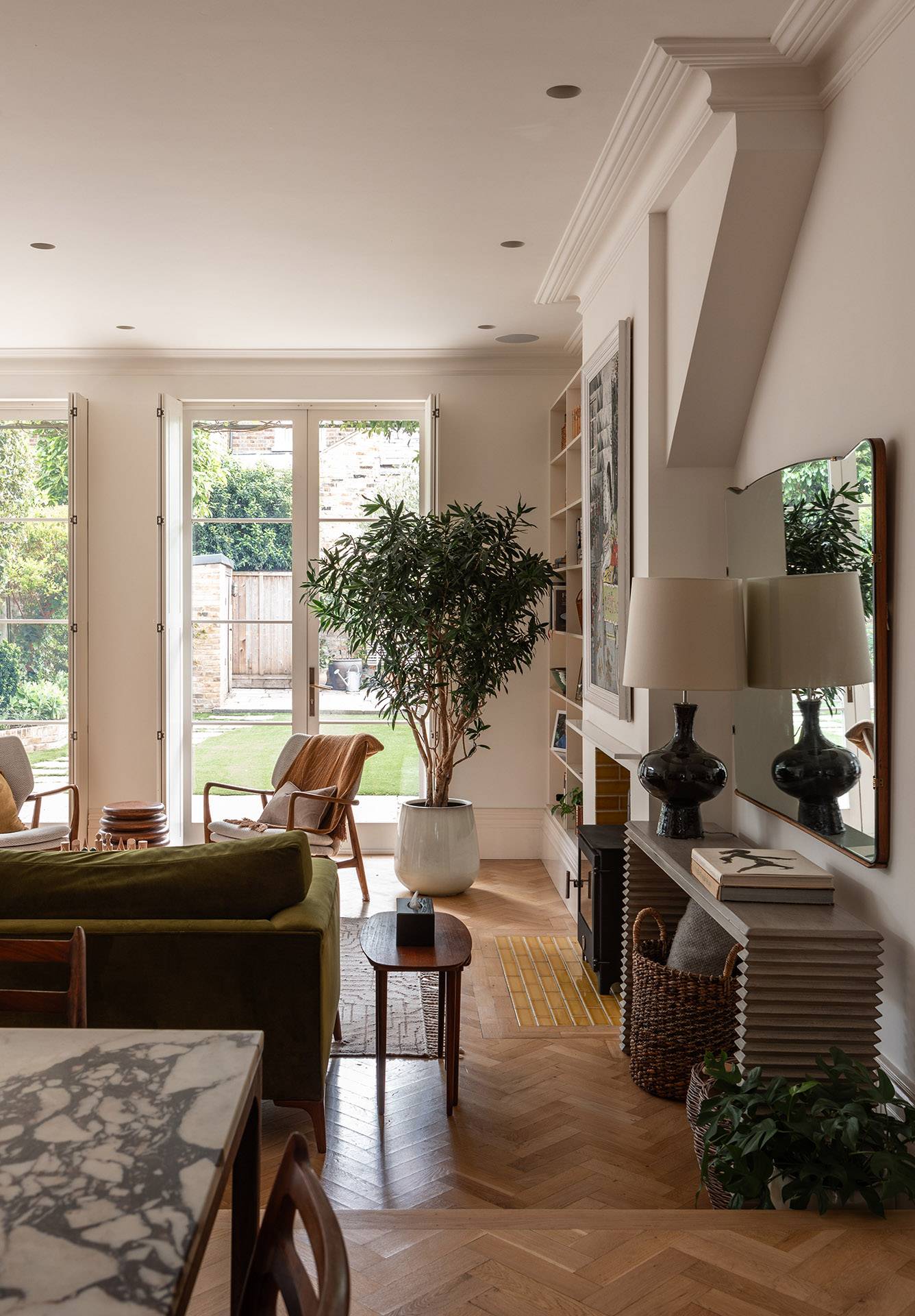Spacious living area with parquet floors and French doors opening onto a sunny garden lawn in Twickenham, TW1, Love Locations.