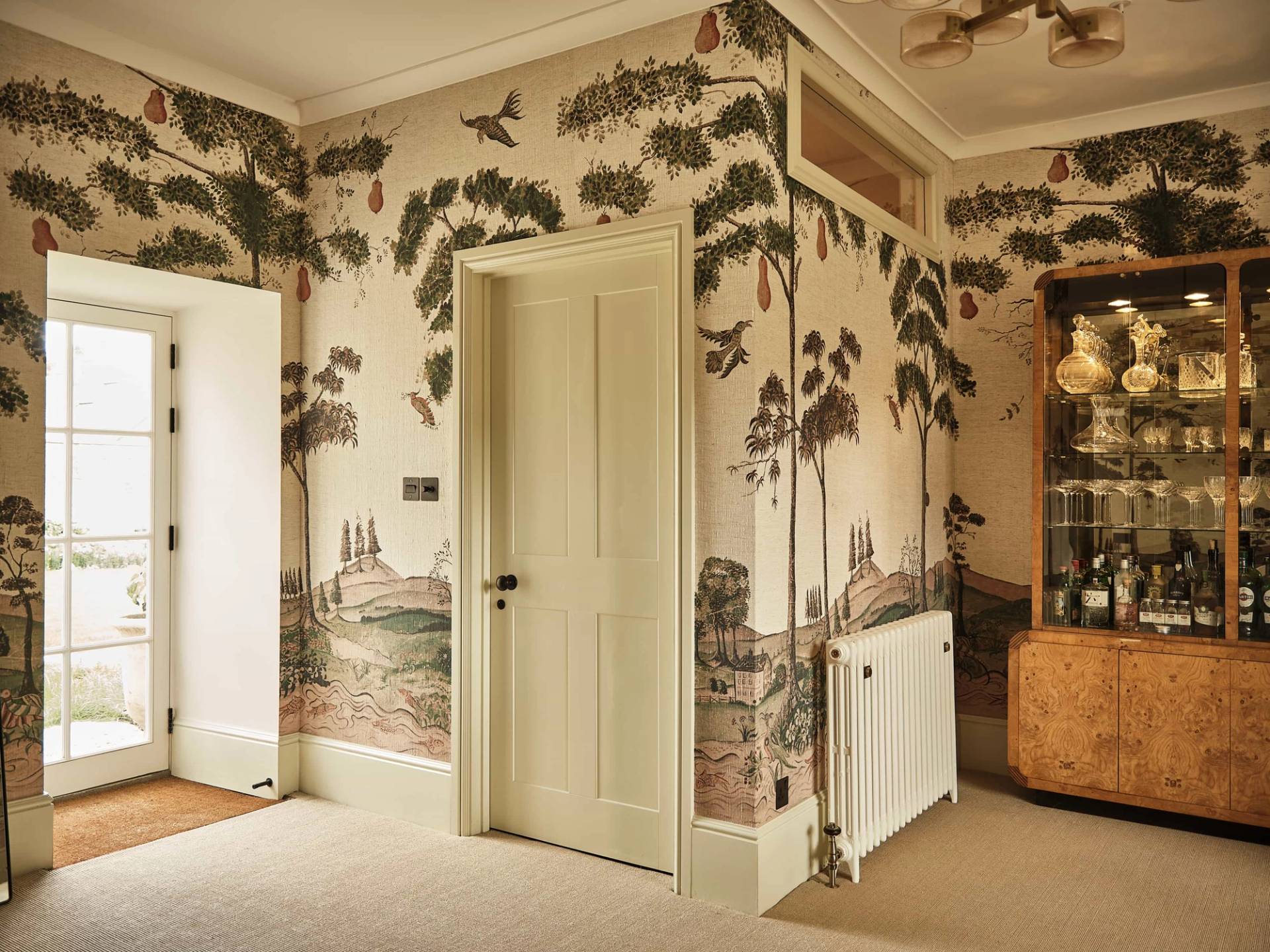 Scenic landscape wall mural wallpaper detail framing a classic painted timber door and radiator, Love Locations OX7.