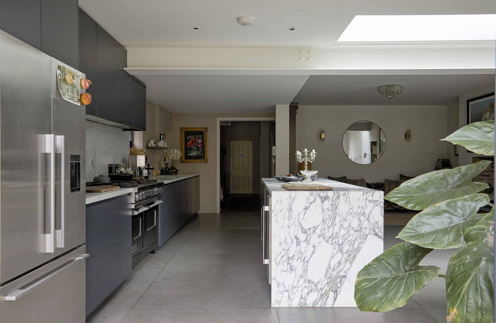 Kitchen extension view looking toward a dark veined marble island and integrated stainless steel gas cooker, Love Locations N16.