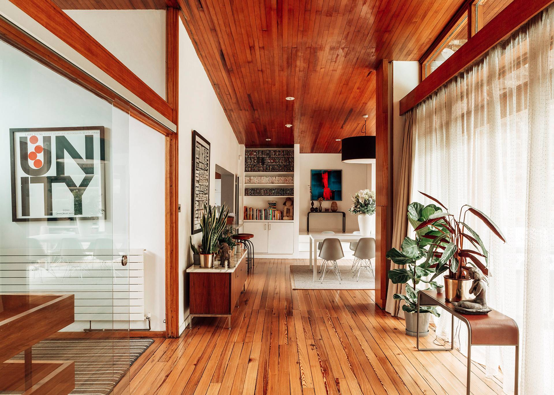 Mid-century hallway transit space featuring polished wooden floors, warm wood panelling, and minimalist artwork, Love Locations BR1.