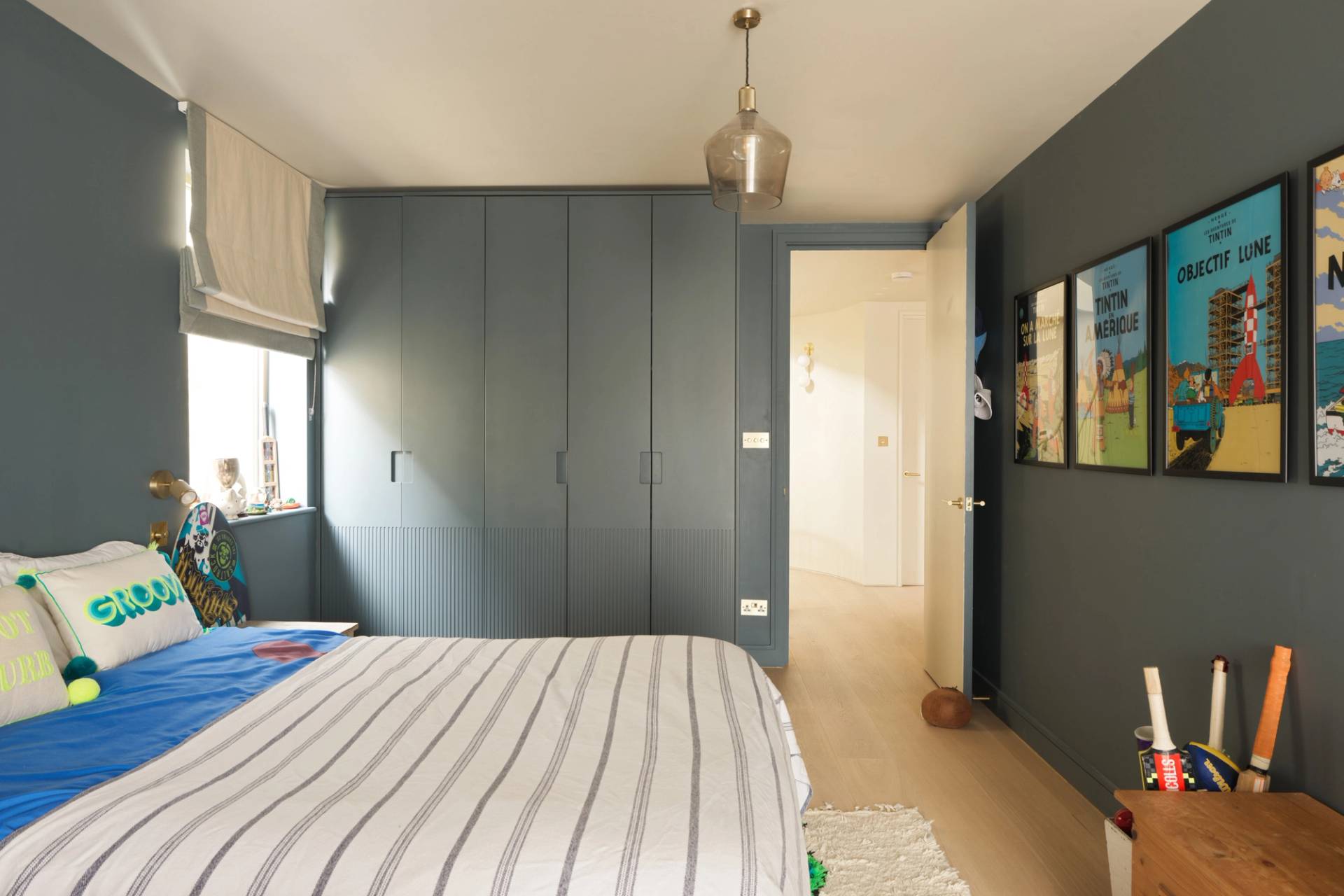 Modern bedroom featuring dark blue fitted wardrobe storage and striped bedding in a London shoot house through Love Locations.