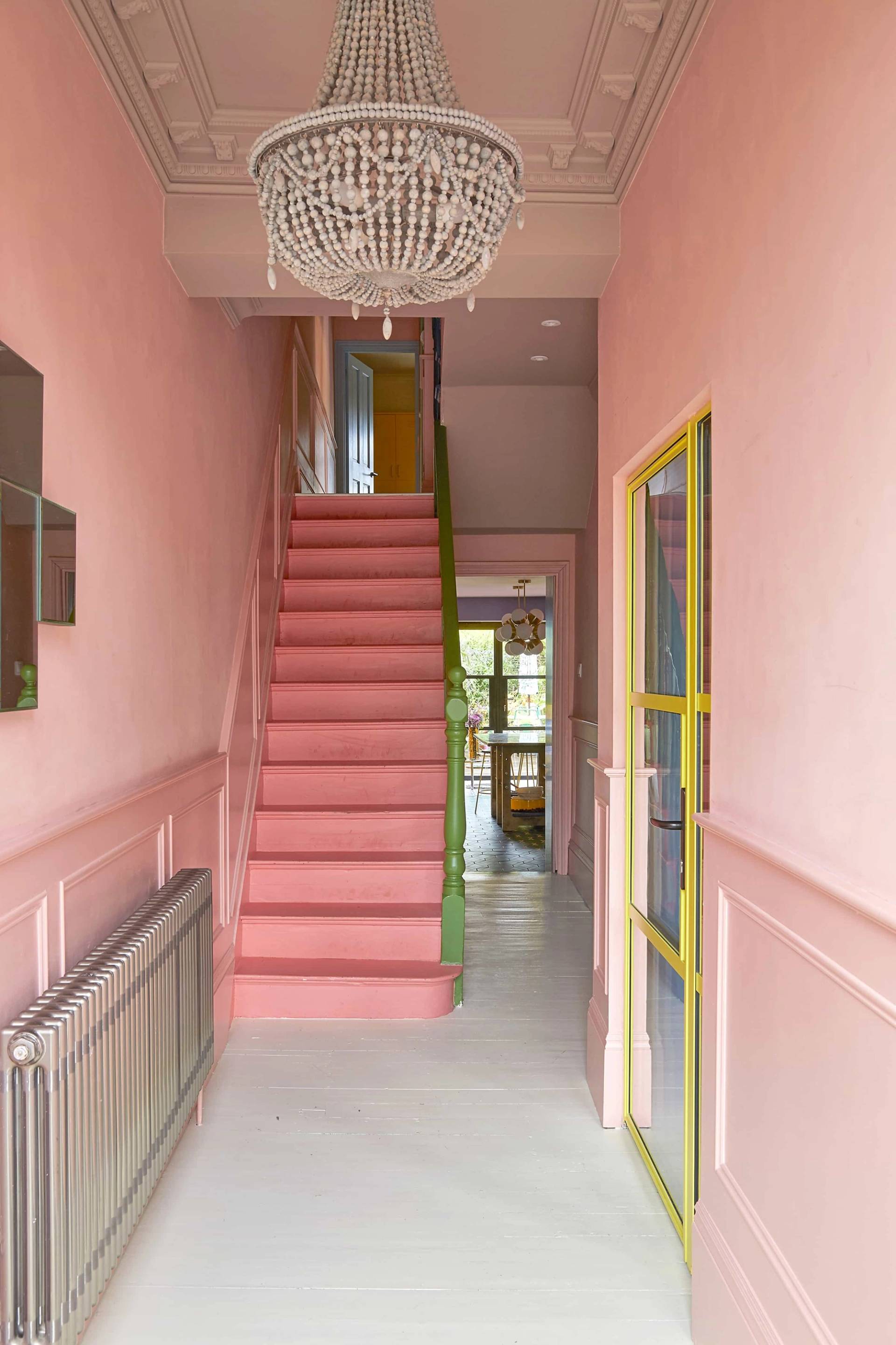 Bubblegum pink entrance hallway featuring a vibrant pink staircase, yellow glass doors, and light wood floors, Love Locations Catford.