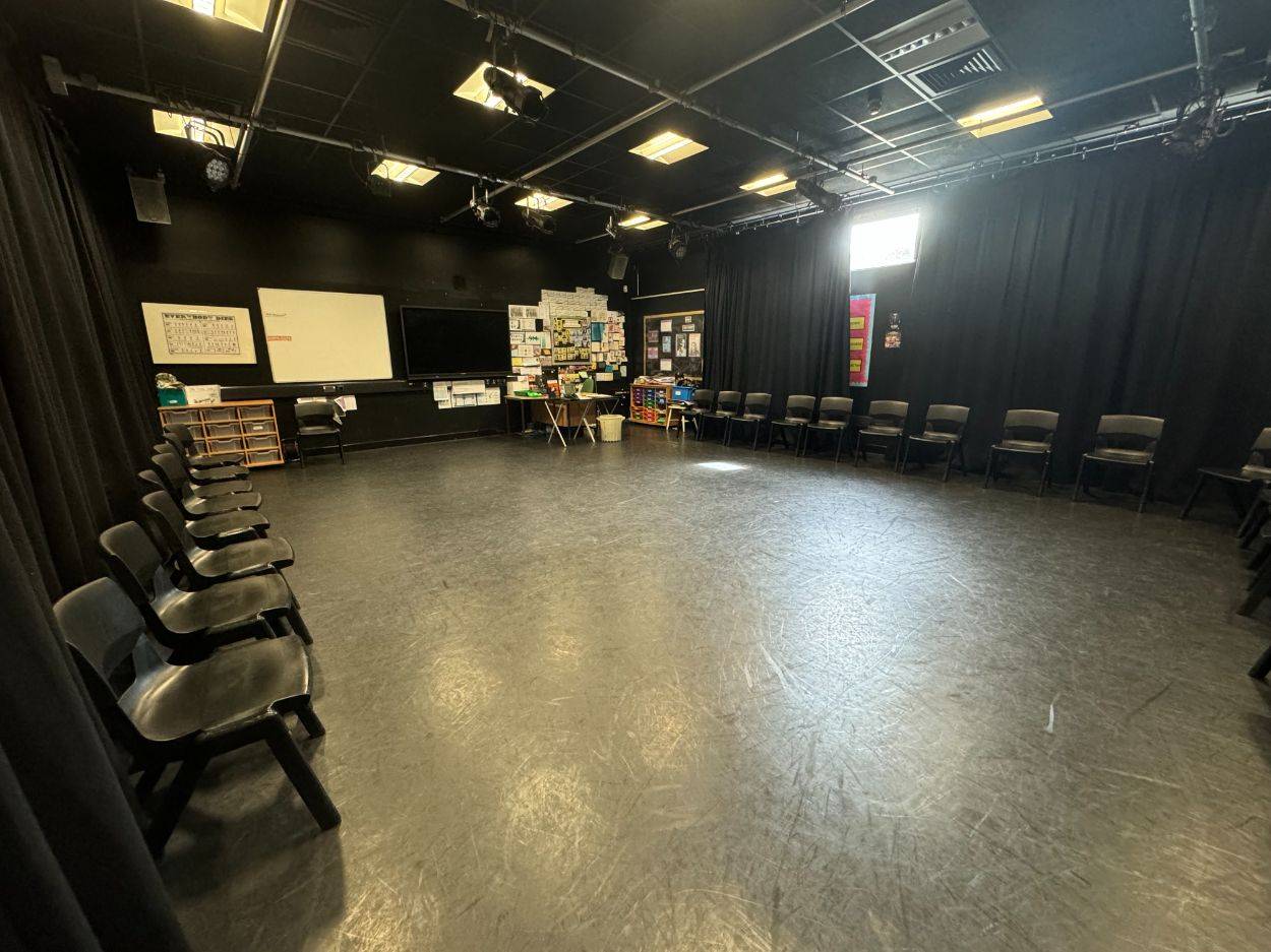 Black box drama studio film location in Barnet N12 featuring dark walls, overhead lighting grid, and black perimeter curtains from Love Locations.
