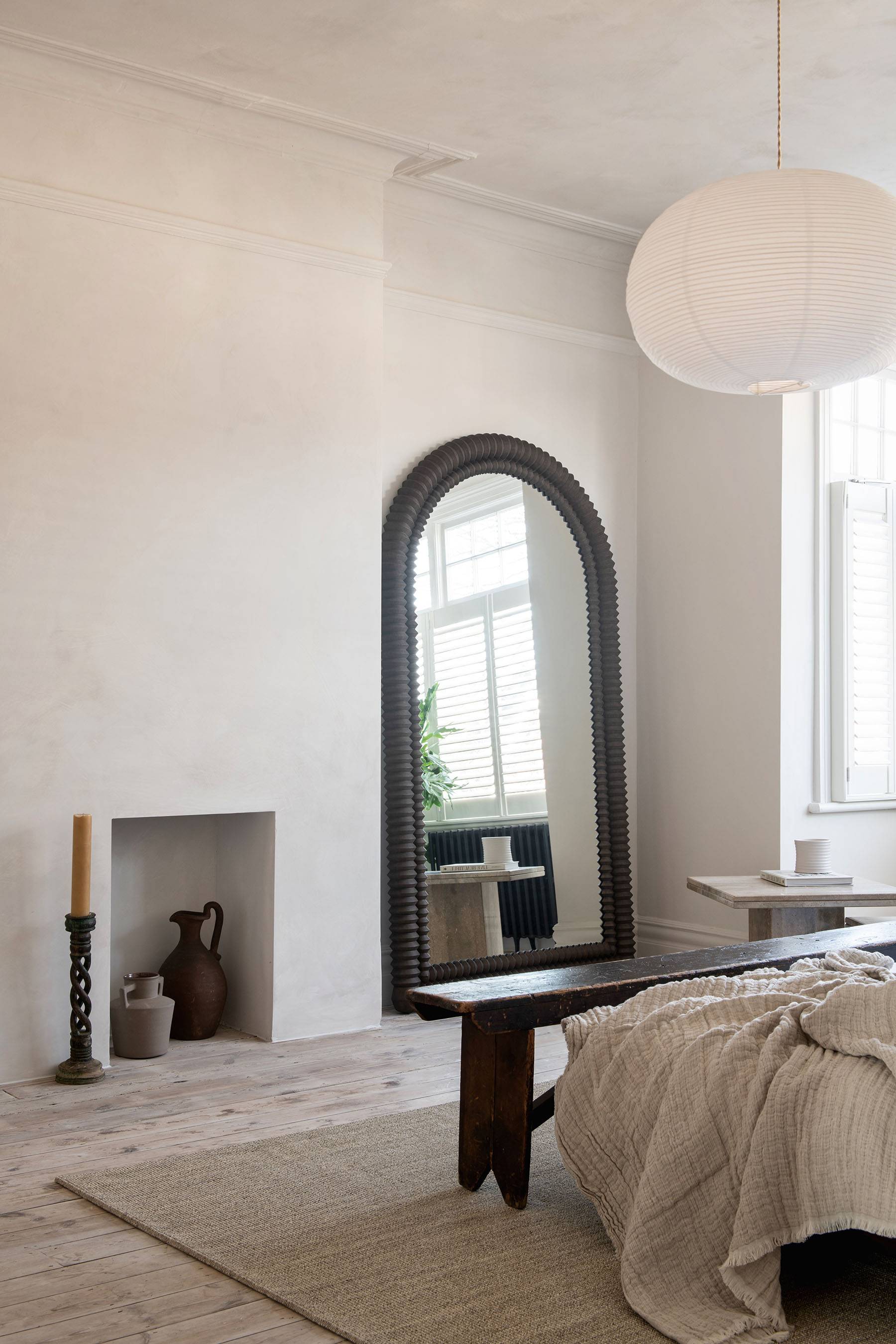 Arched hallway transition leading through micro-cement plaster walls into a bright bedroom suite, Love Locations SW16.