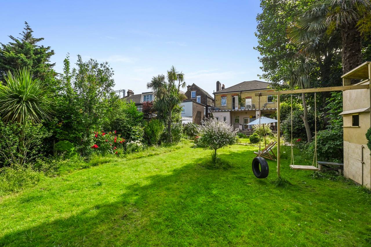 Spacious residential lawn garden featuring a tree swing and mature greenery, perfect for family brand advertising, Love Locations E7.
