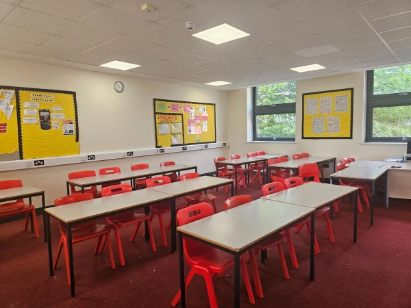 Empty high school classroom shoot location with rows of student desks, red chairs, and ample natural light, Love Locations Buckinghamshire.