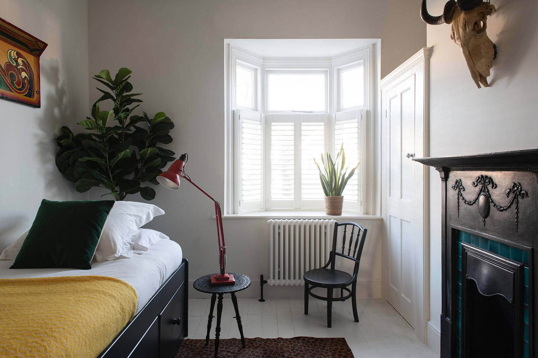 Dark teal bedroom featuring a wooden bed frame, oak bedside table, and line art prints on dark walls, Love Locations SW16.