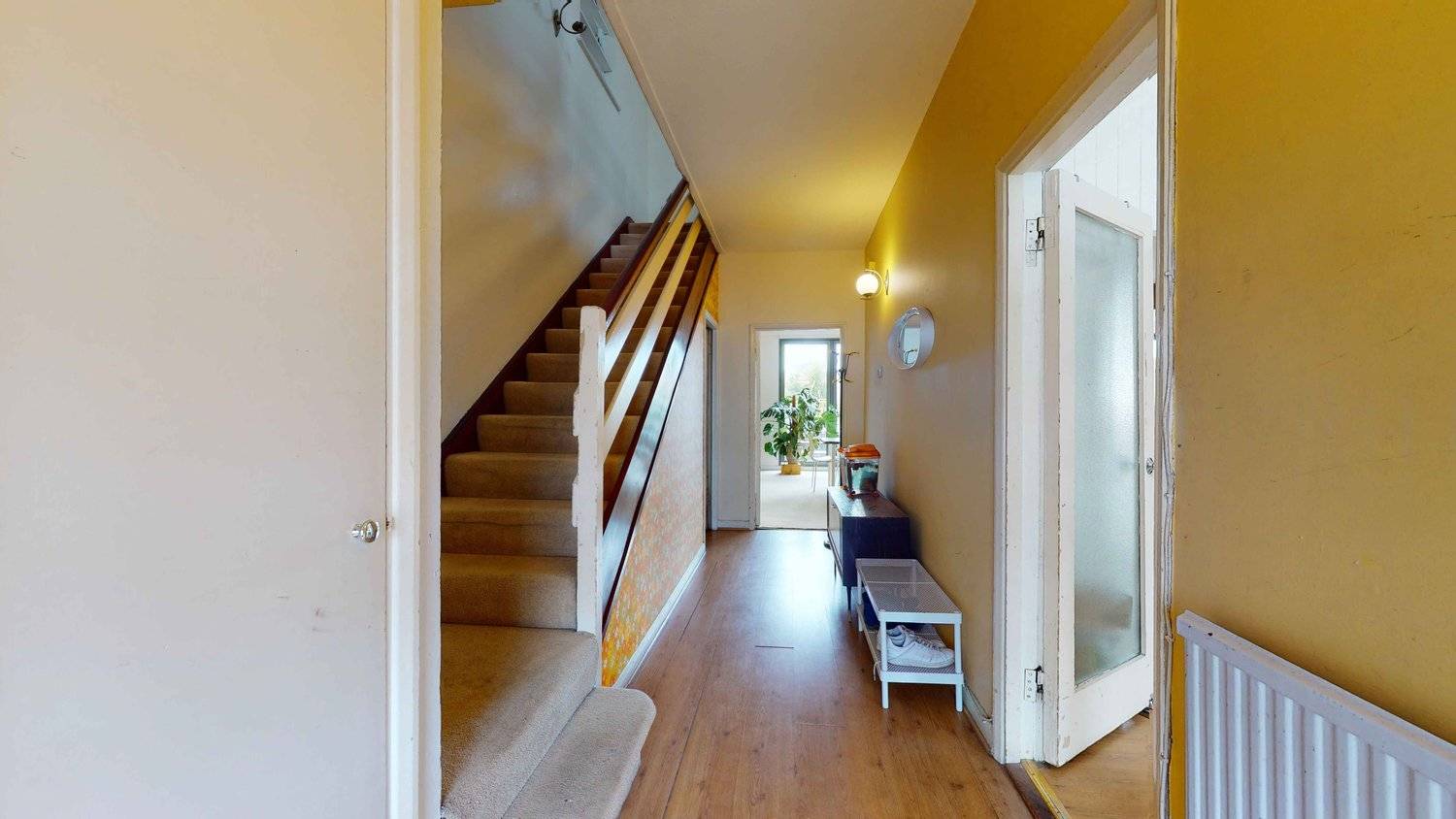 Retro hallway entrance with mustard yellow painted walls, timber staircase banisters, and wood flooring, Love Locations SW16.