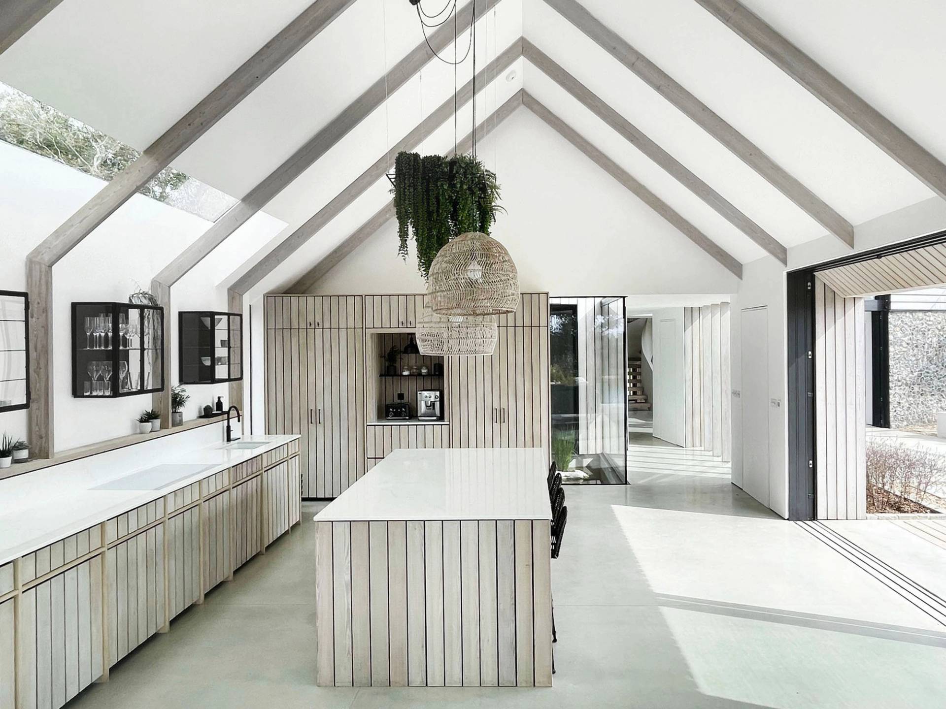 Spacious double-height kitchen and dining space with light timber slatted cabinetry, central island, and skylights, perfect for food media filming, Love Locations.