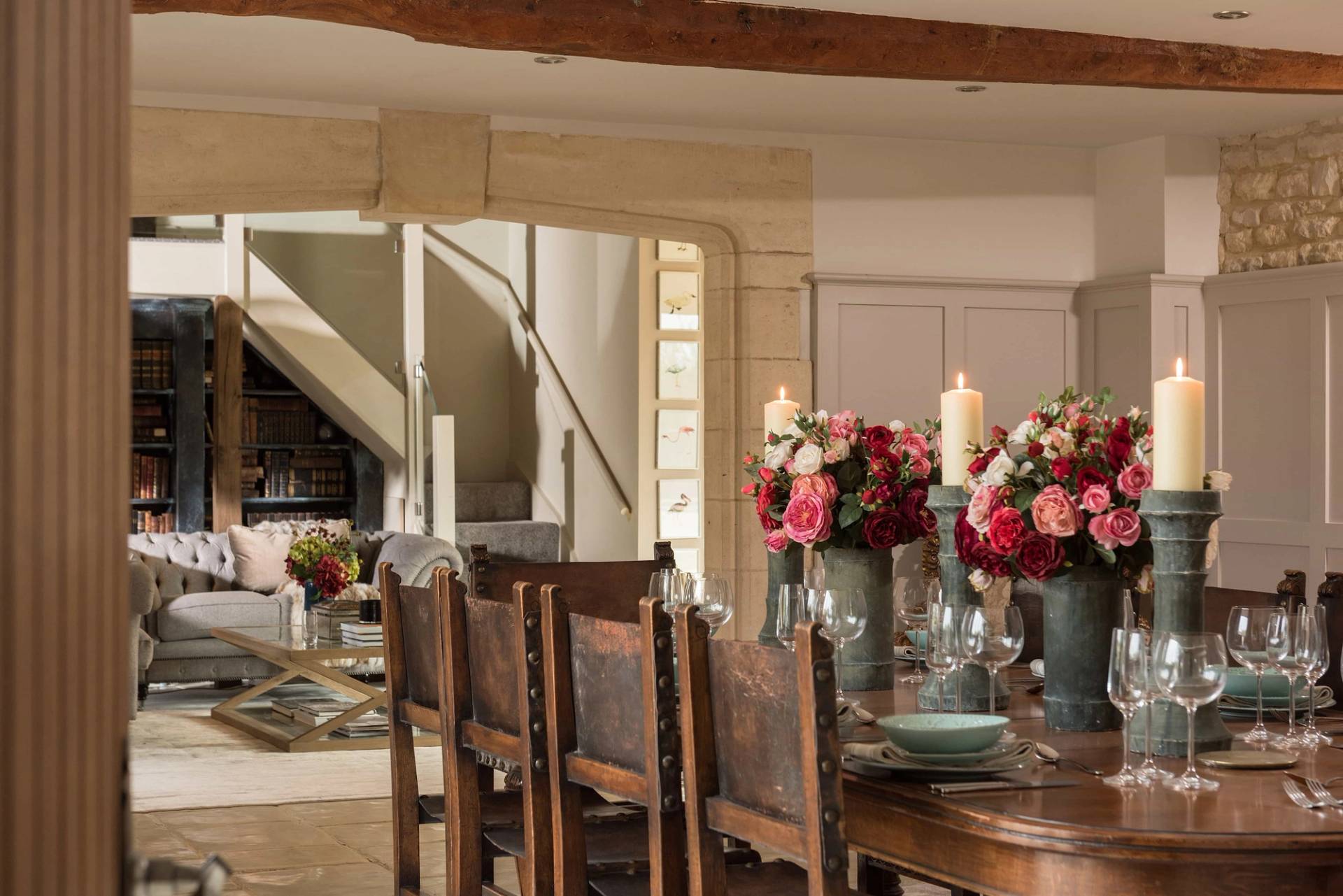 Detailed view of an elegant rustic wooden dining set with a stone archway backdrop in a Mediterranean-inspired Cotswold home by Love Locations.