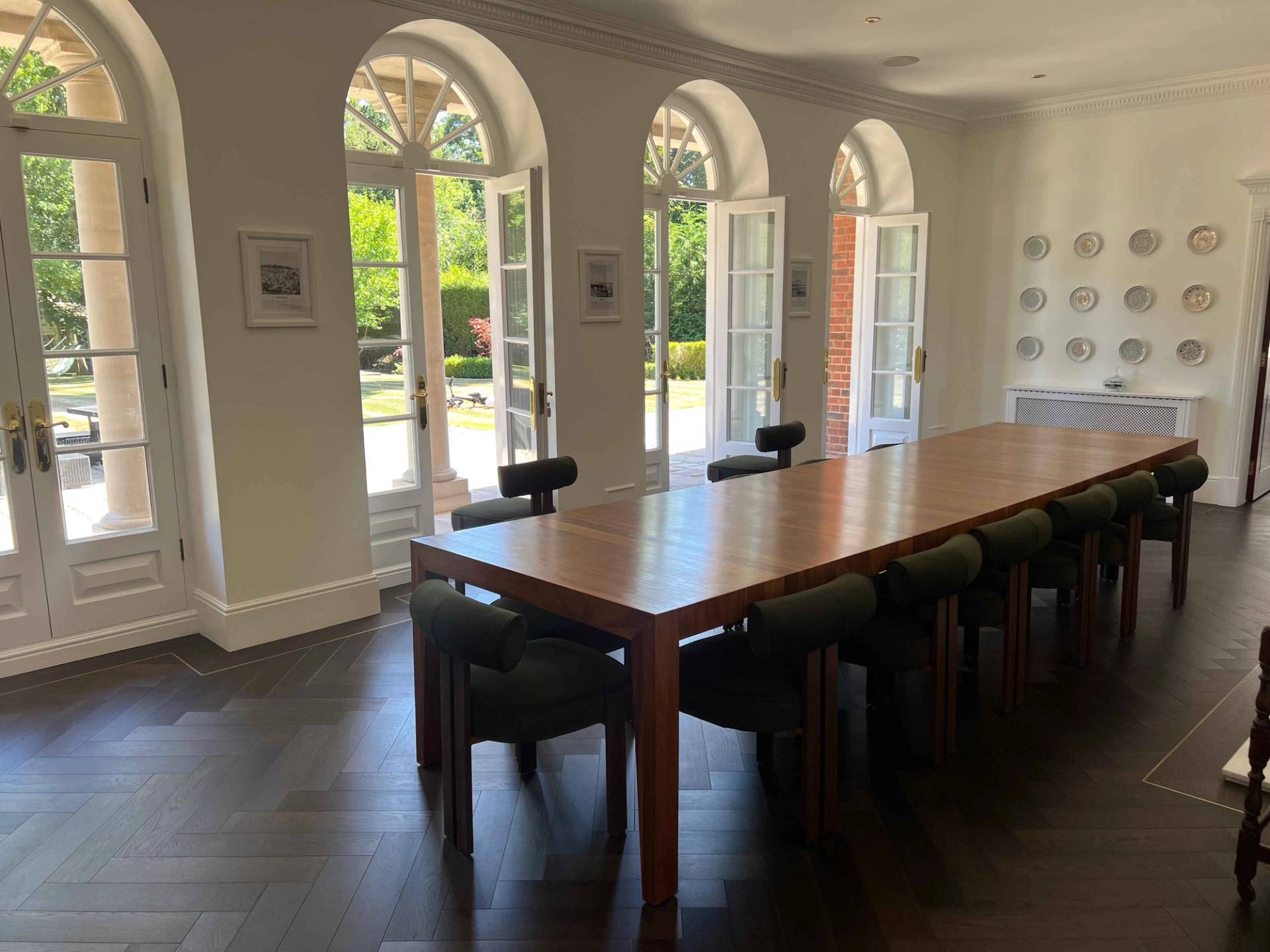 Arched glass french doors framing garden views in a formal dining room with mahogany furniture, Love Locations BR7.
