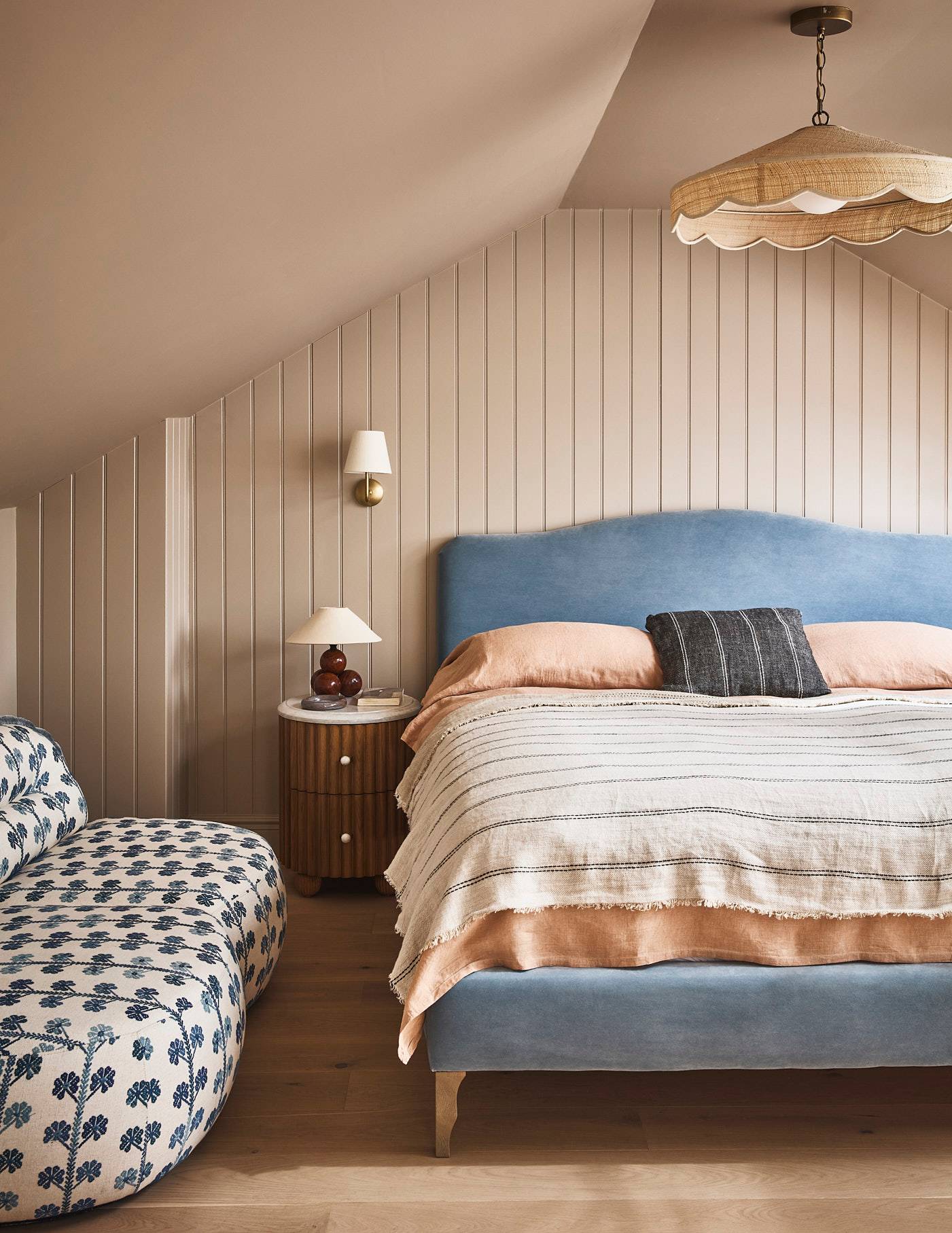 Cozy attic bedroom with vertical wood panelling, blue upholstered bed frame, and soft striped bedding, Love Locations SE21.