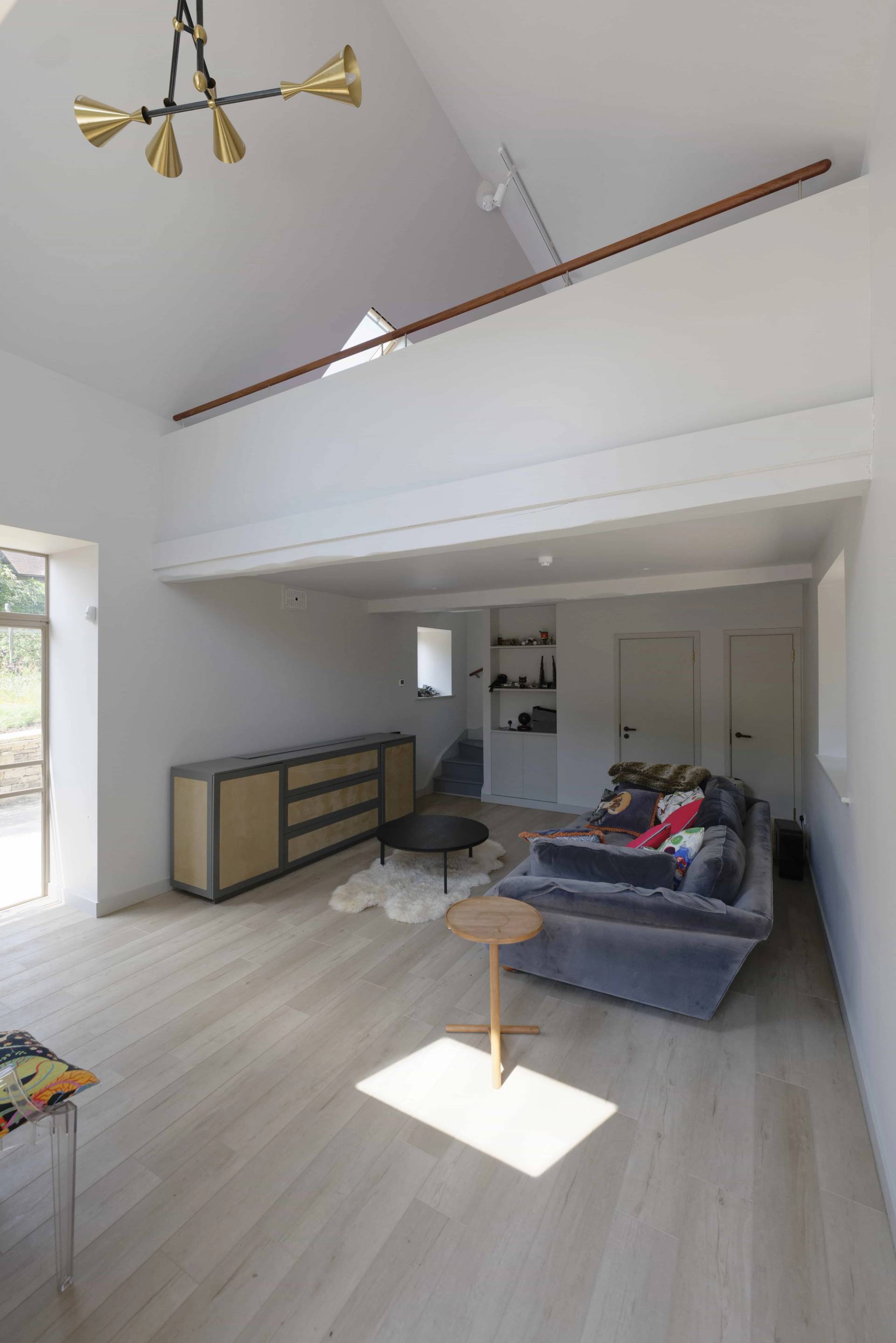 Contemporary loft lounge featuring a grey sectional sofa, sloped ceilings, and wood flooring, Love Locations OX7.