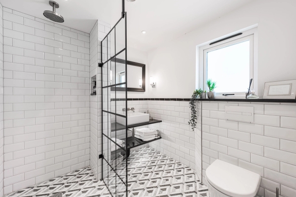 Stylish monochrome walk-in shower room with geometric floor tiles and crittall-style black framed glass doors, Love Locations.