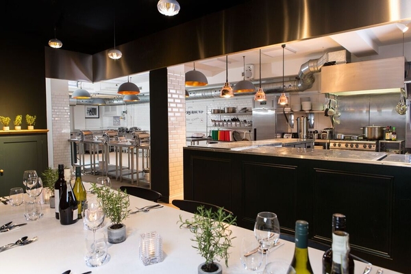 Exclusive private dining room setup with an dressed table looking into an open commercial kitchen set, curated by Love Locations.