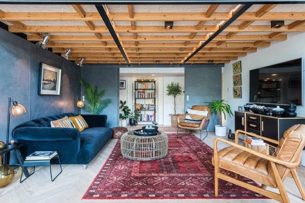 Stylish snug room location space featuring exposed wooden ceiling joists, a blue velvet sofa, and a traditional red rug, Love Locations.