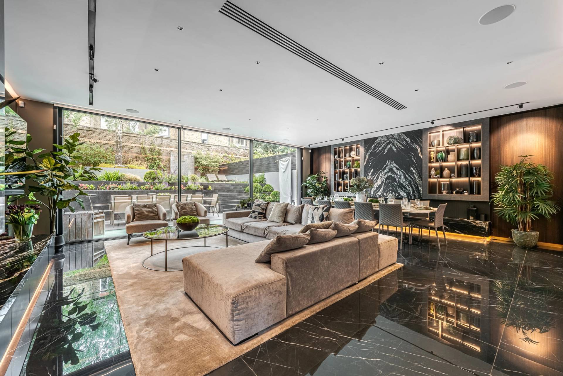 Open-plan reception room view showing a plush velvet corner sofa, rug, and black marble tiles in Wandsworth, Love Locations SW11.