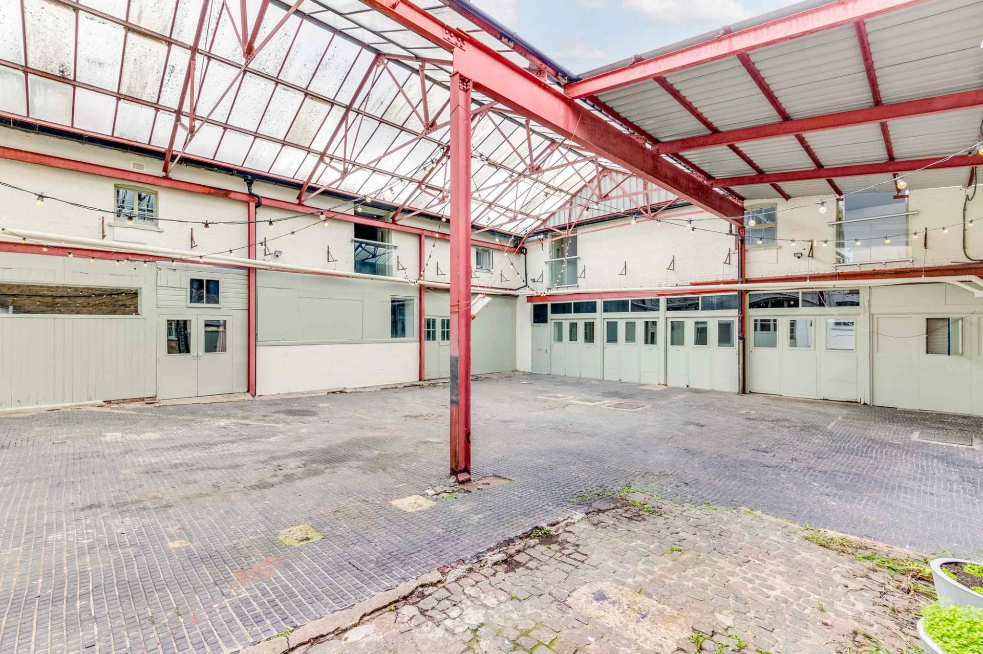 Urban industrial location featuring red steel framework and distressed paving for music videos, booked through Love Locations.