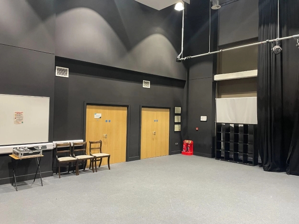 Love Locations production staging room RG30: Industrial dark-painted performance hall corner with double exit doors and storage lockers, ideal for backstage scenes and short films.