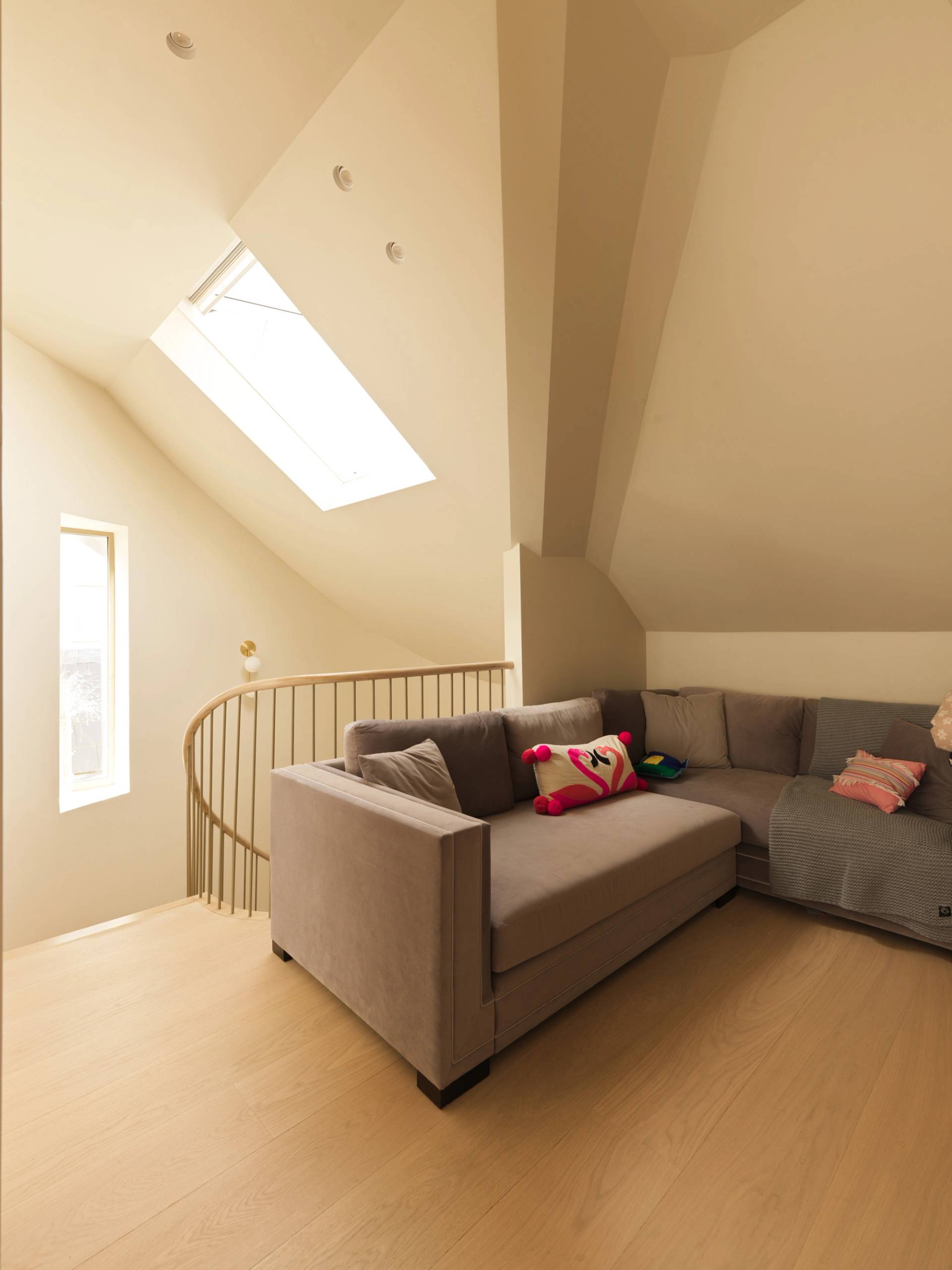 Top floor lounge and loft space with sloping ceilings, skylight window, and L-shaped corner sofa through Love Locations.