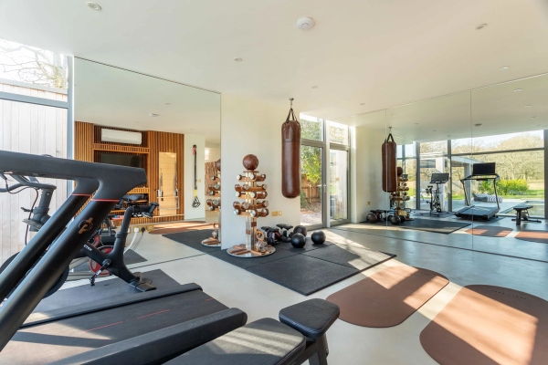 Love Locations commercial fitness studio location Godalming Surrey GU8: Fully equipped home gym with weight racks, mirrored walls, and hanging heavy boxing bags, tailored for fitness apparel filming.
