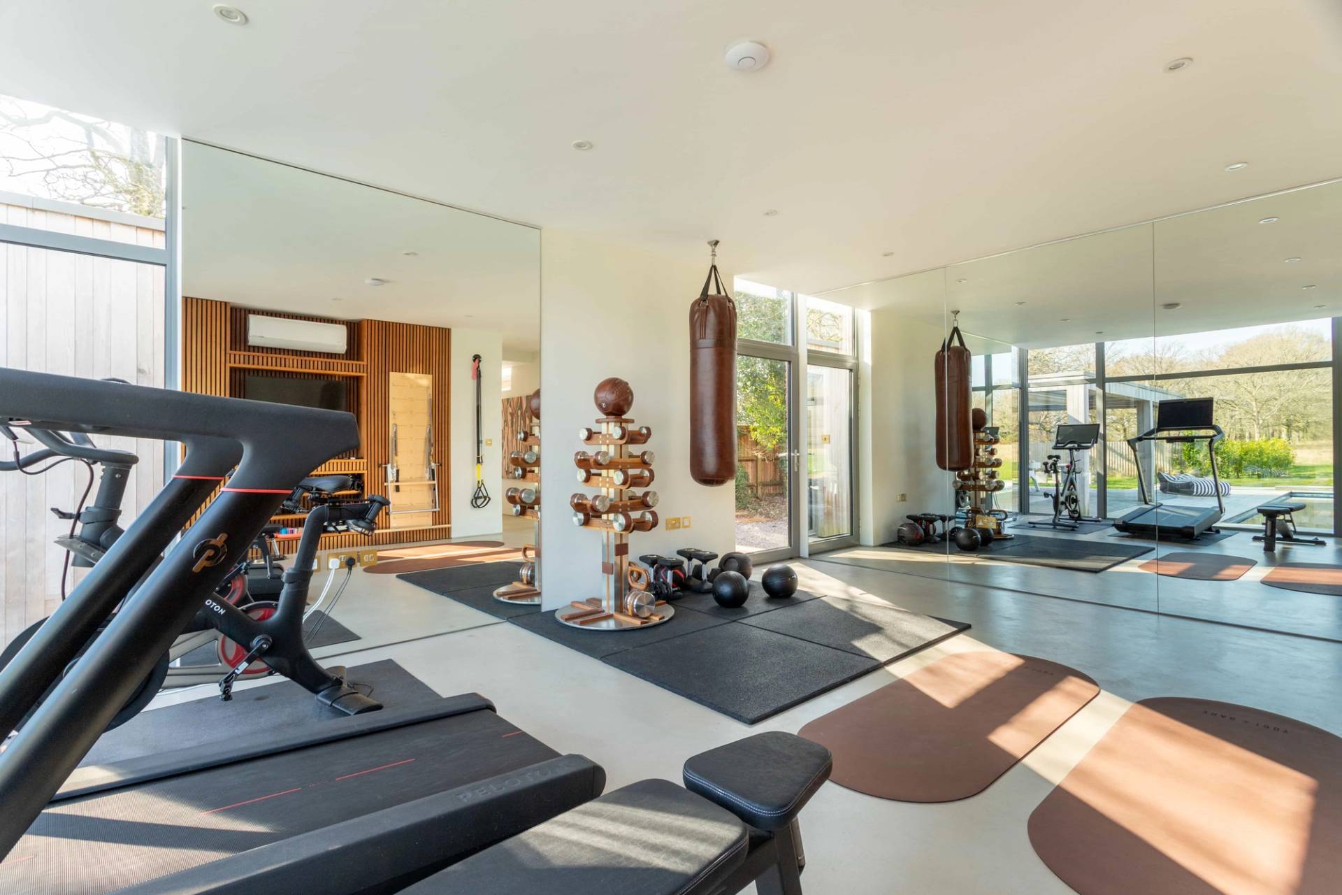 Love Locations commercial fitness studio location Godalming Surrey GU8: Fully equipped home gym with weight racks, mirrored walls, and hanging heavy boxing bags, tailored for fitness apparel filming.