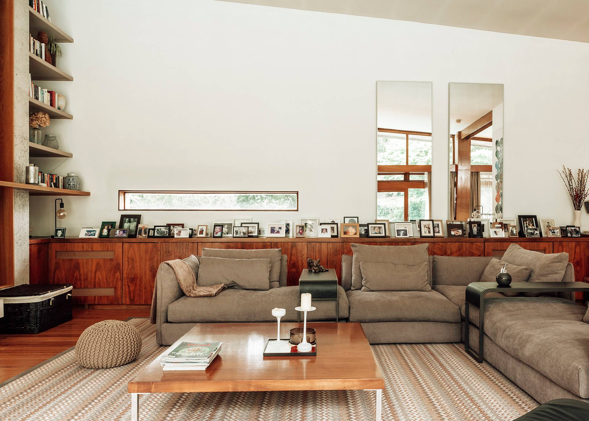 Mid-century modern living room seating area looking toward a long row of framed family photographs and low cabinetry, Love Locations.