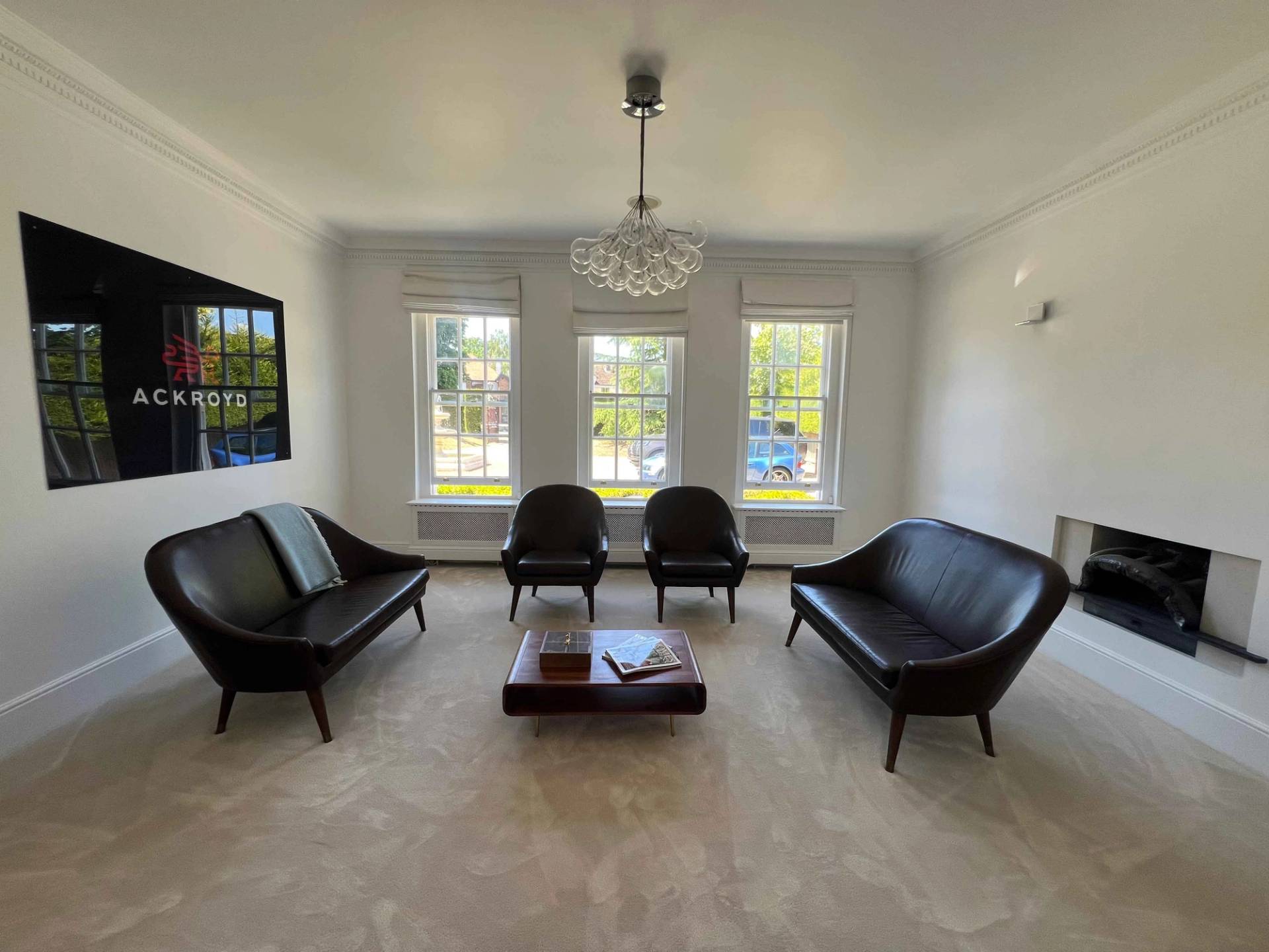 Dark leather sofa seating set beneath triple sash windows in a neutral reception room, Love Locations BR7.
