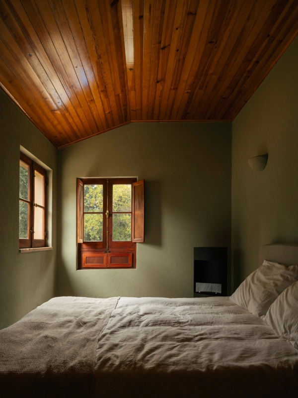 Earthy green bedroom with sloped timber ceiling, wooden shutters, and minimalist bed linen, Love Locations 2705-064.