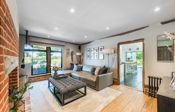 Spacious residential living room location featuring a grey leather corner sofa and hardwood flooring, managed by Love Locations.