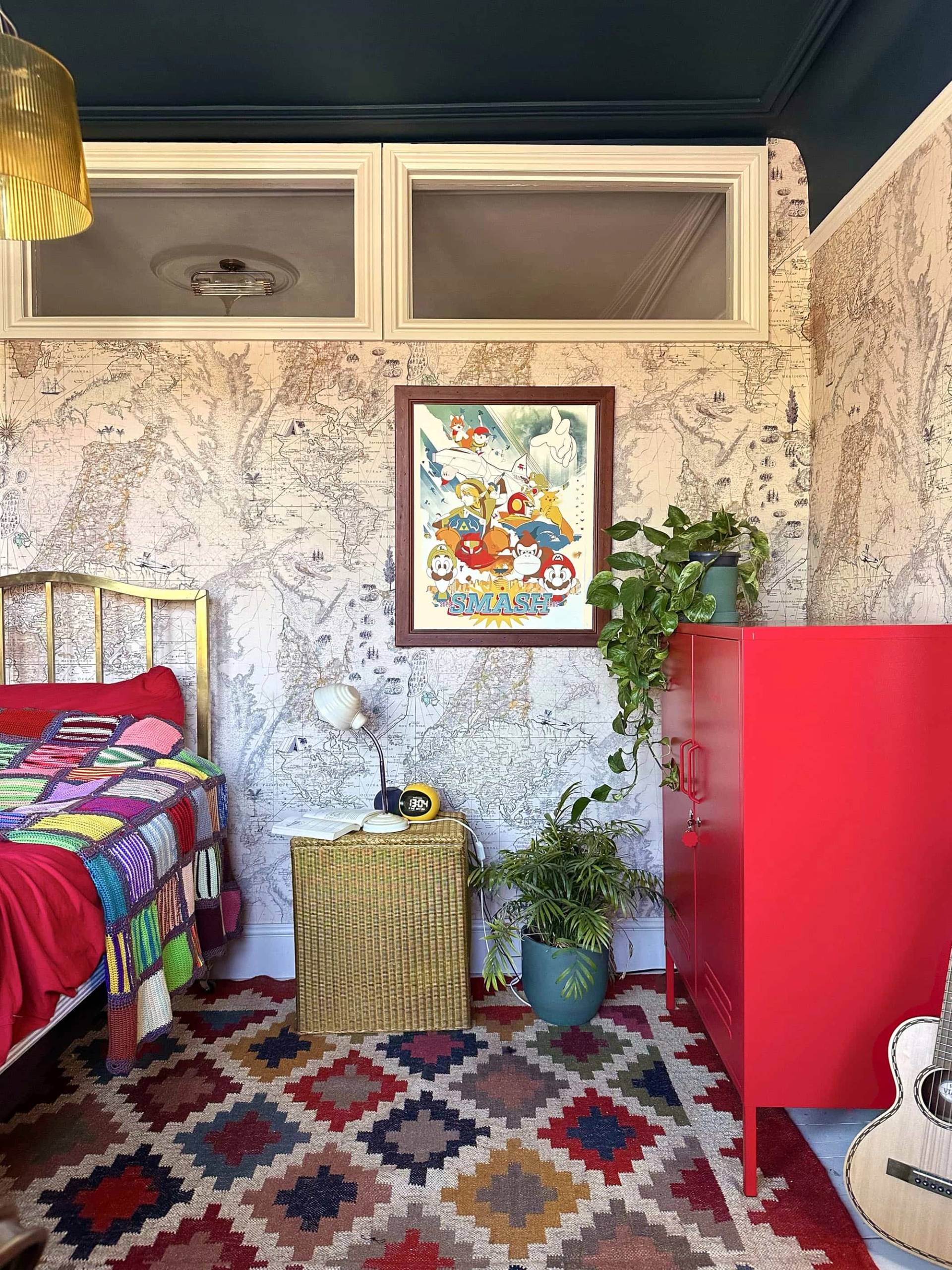 Eclectic guest bedroom layout with red chest, floral wallpaper, and brass bedstead, Love Locations N13.