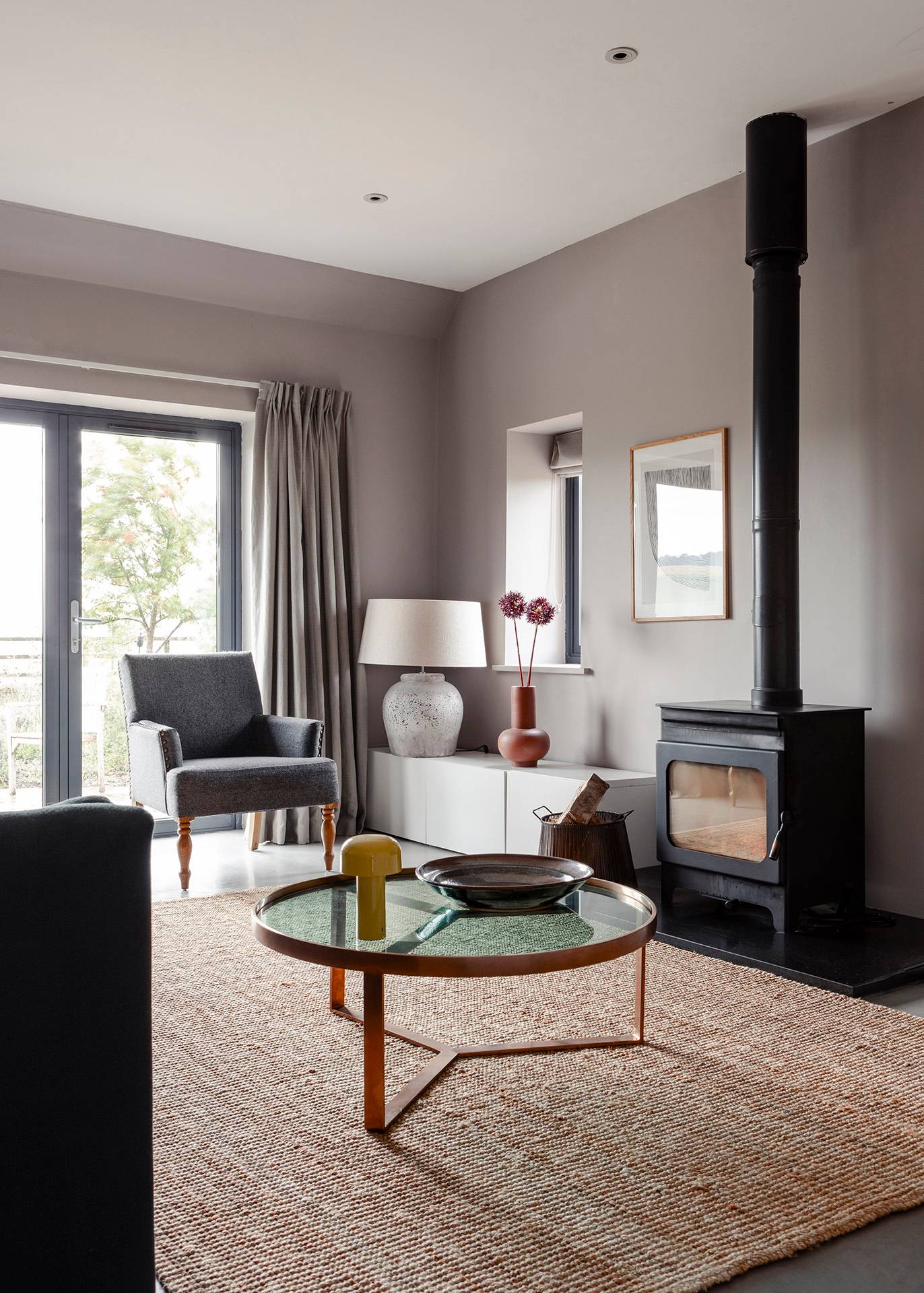 Cozy sitting room featuring a black wood-burning stove, round wooden coffee table, and soft grey walls, Love Locations SN8.
