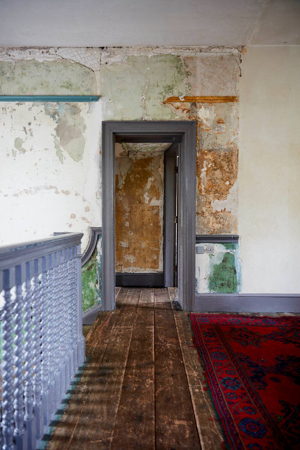 Distressed upper landing corridor with dark blue balustrades, peeling wallpaper, and wide floorboards, perfect for gritty film backdrops, Love Locations SE8.