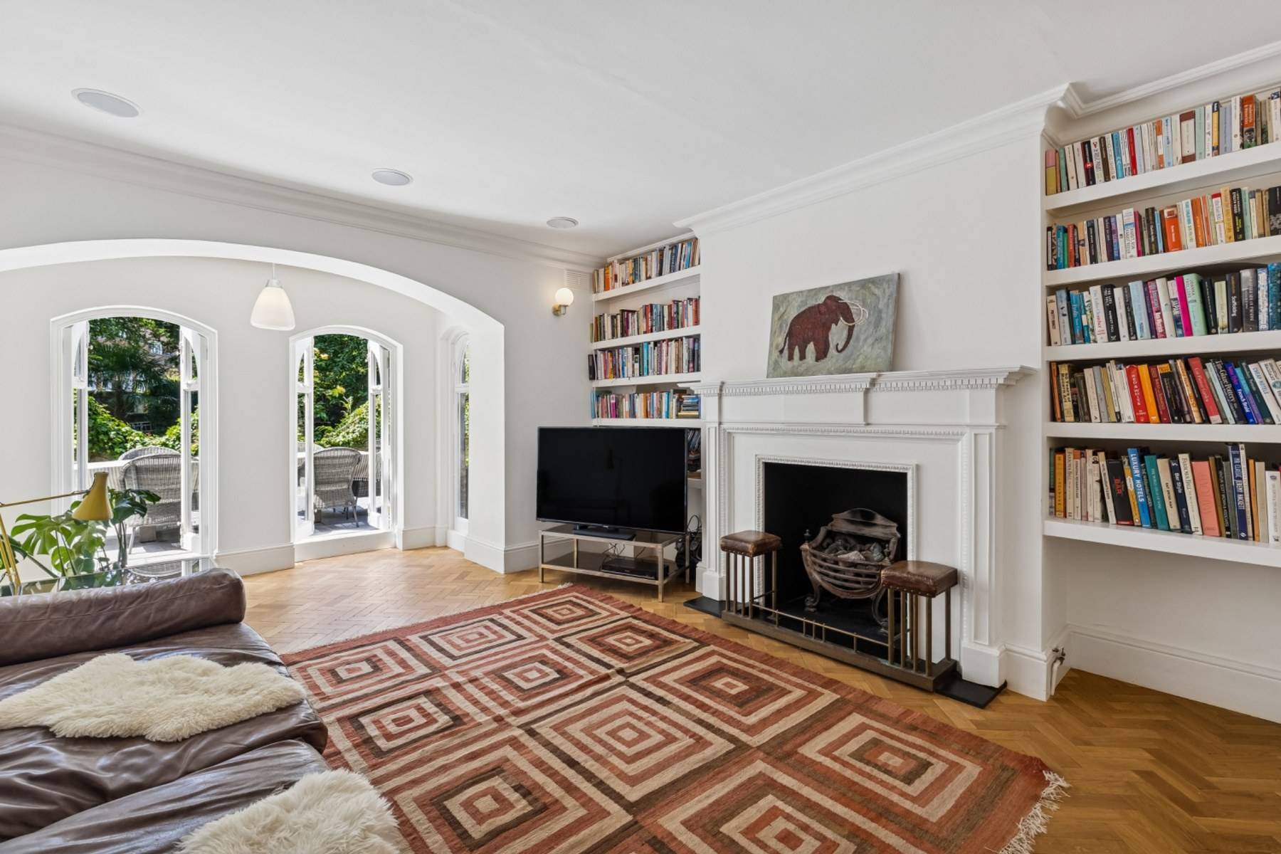 Bright sitting room photoshoot space with arched double doors opening to a garden terrace in Hampstead by Love Locations.