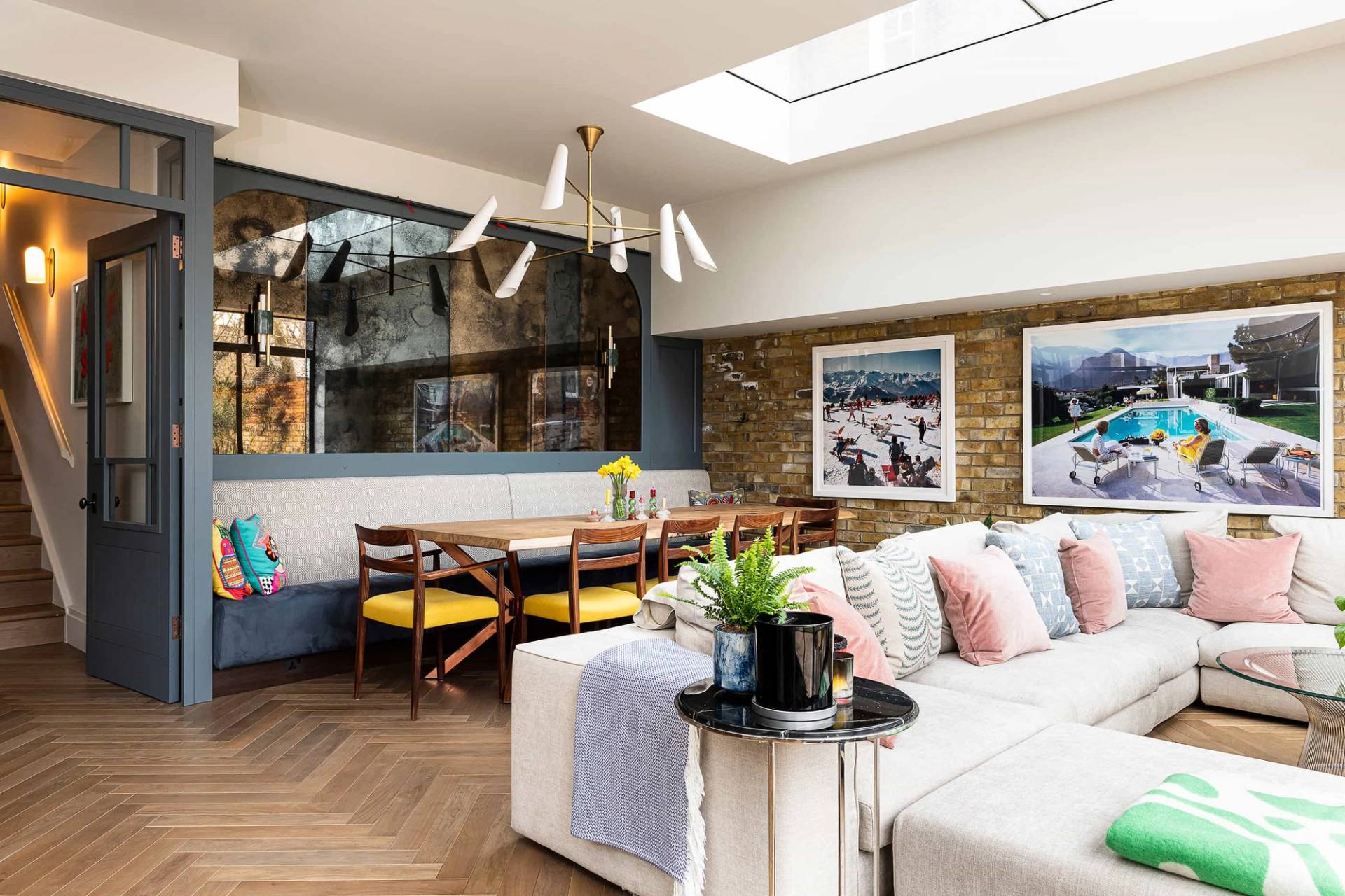Bright open-plan lounge featuring a light grey sectional sofa, banquette dining booth, and brick wall accents, Love Locations.