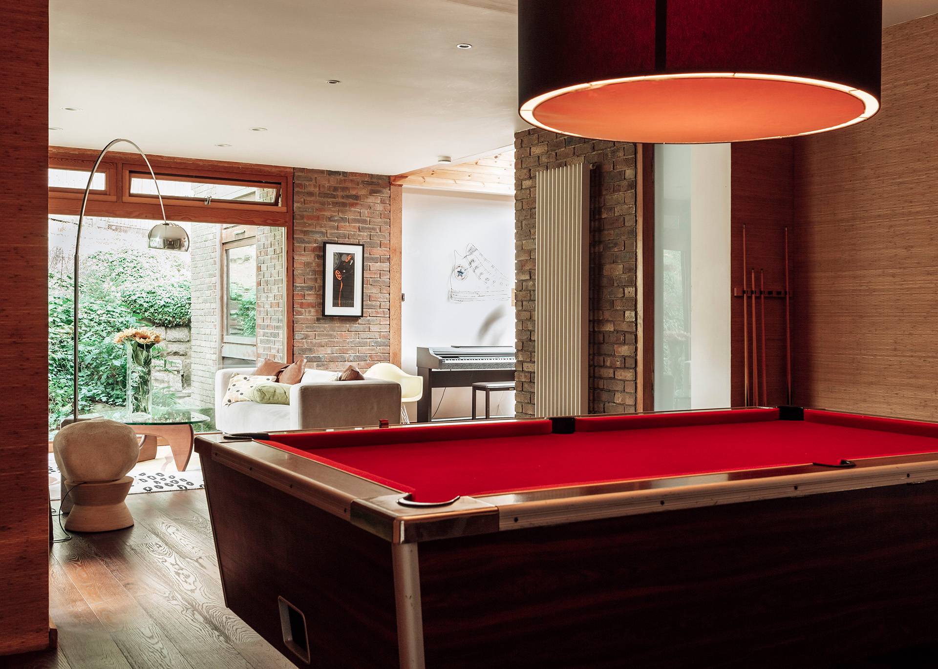 Mid-century entertainment room featuring a classic pool table with a red felt top, wood panelling, and atmospheric lighting, Love Locations BR1.