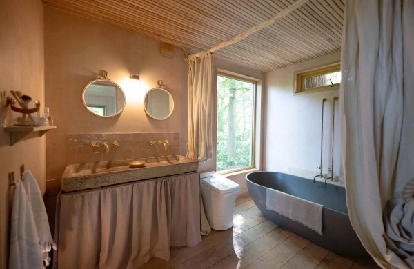Luxury cabin bathroom location featuring twin vanity stone sinks, brass hardware, and a freestanding dark grey bathtub, Love Locations Herefordshire.