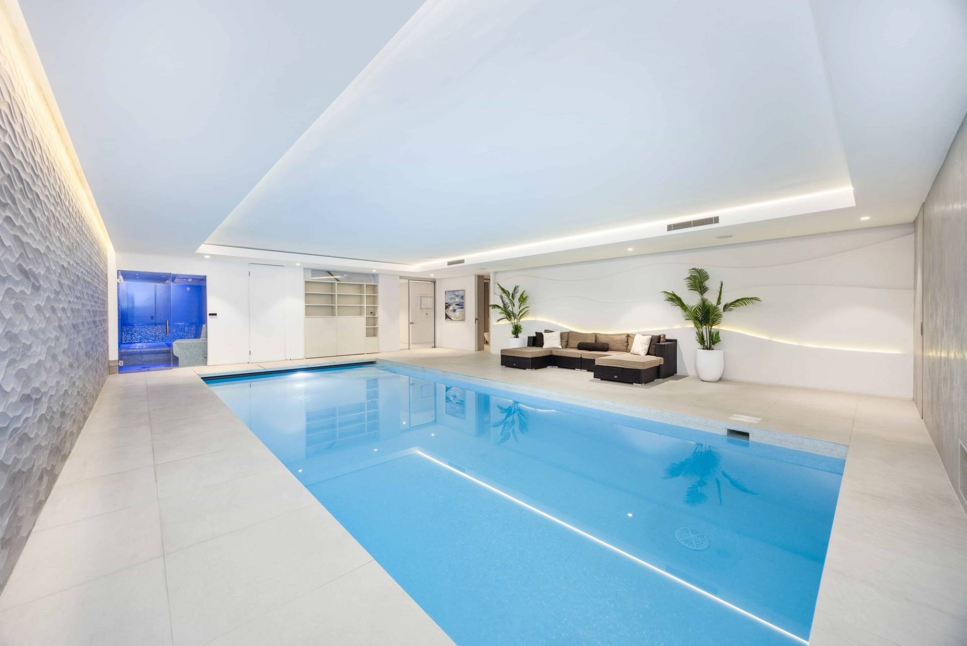 Spacious indoor heated swimming pool with pristine blue water and plush lounge seating, Love Locations WD7.