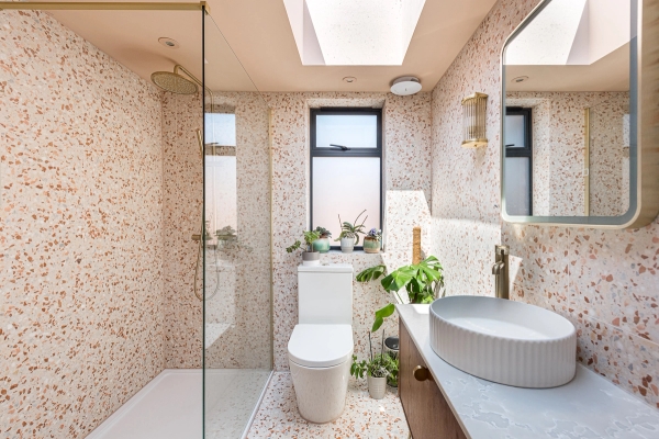 Modern terrazzo-tiled family bathroom location featuring a glass walk-in shower enclosure and a floating vanity sink, Love Locations.