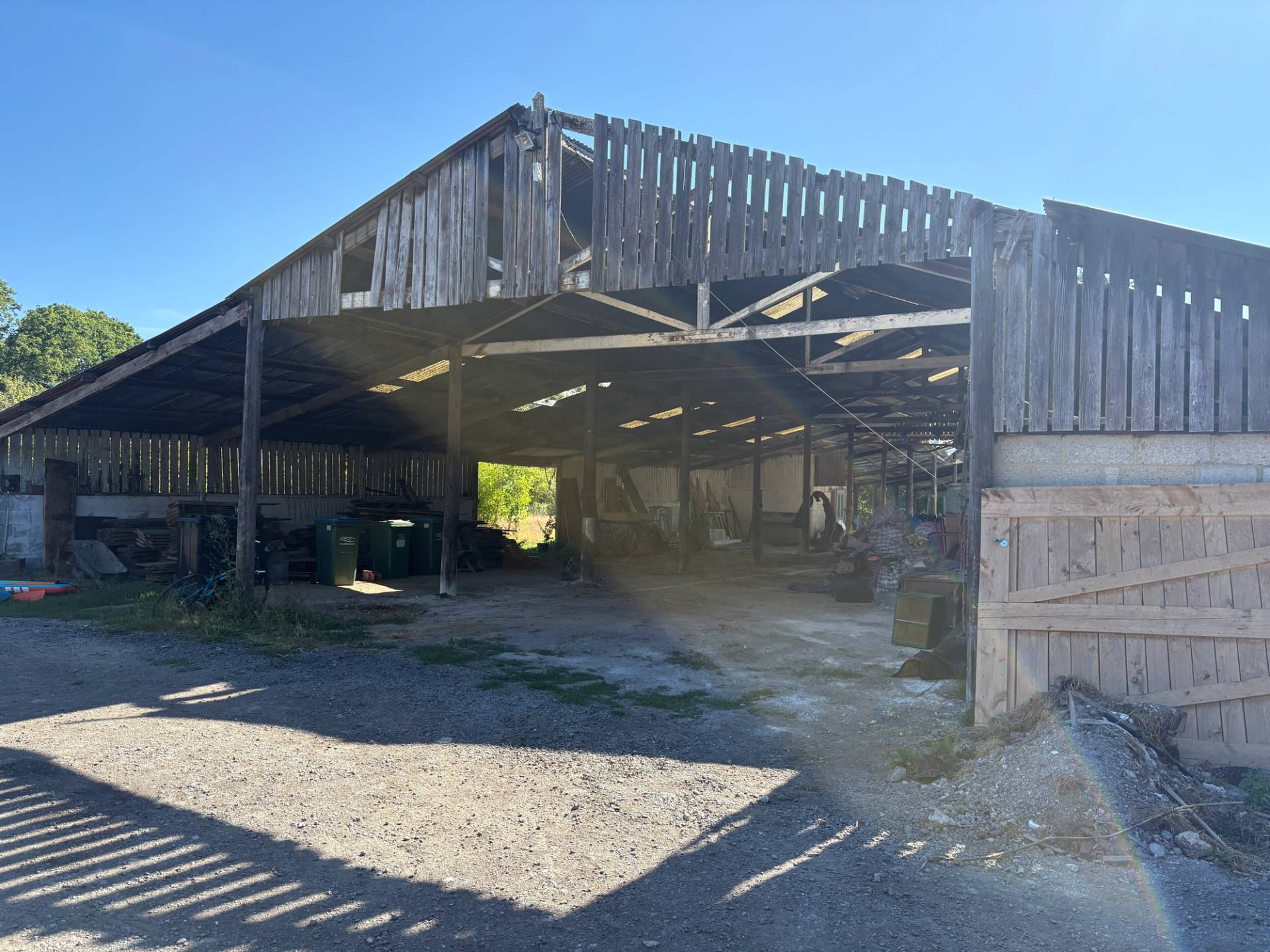 Large wooden open Dutch barn facade with slatted timber gables and gravel yard in South Chailey, Love Locations BN8.