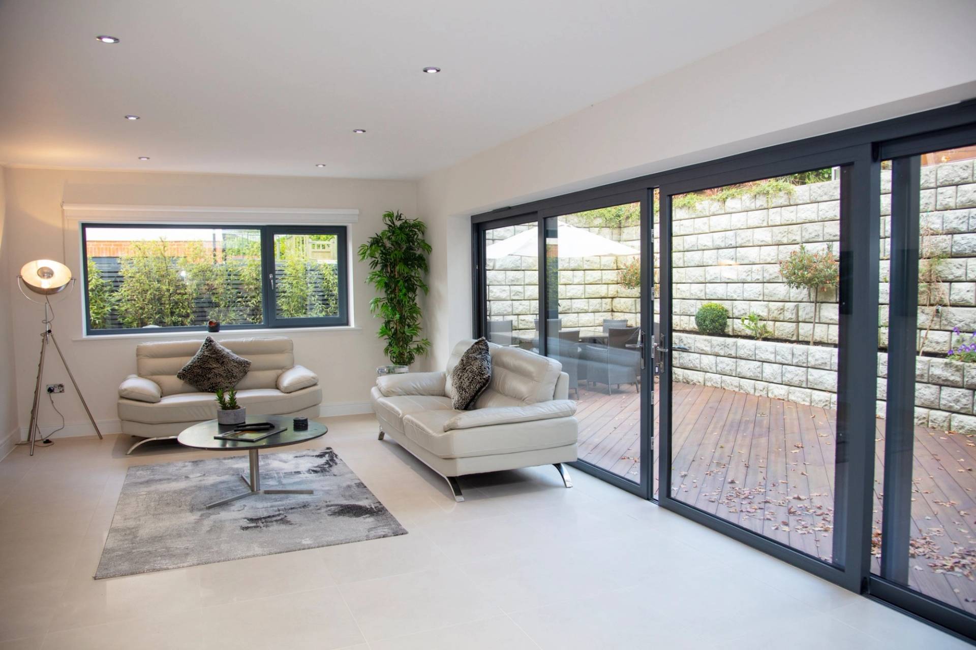 Spacious living room location space opening directly onto an outdoor timber decking terrace via large sliding doors, managed by Love Locations.