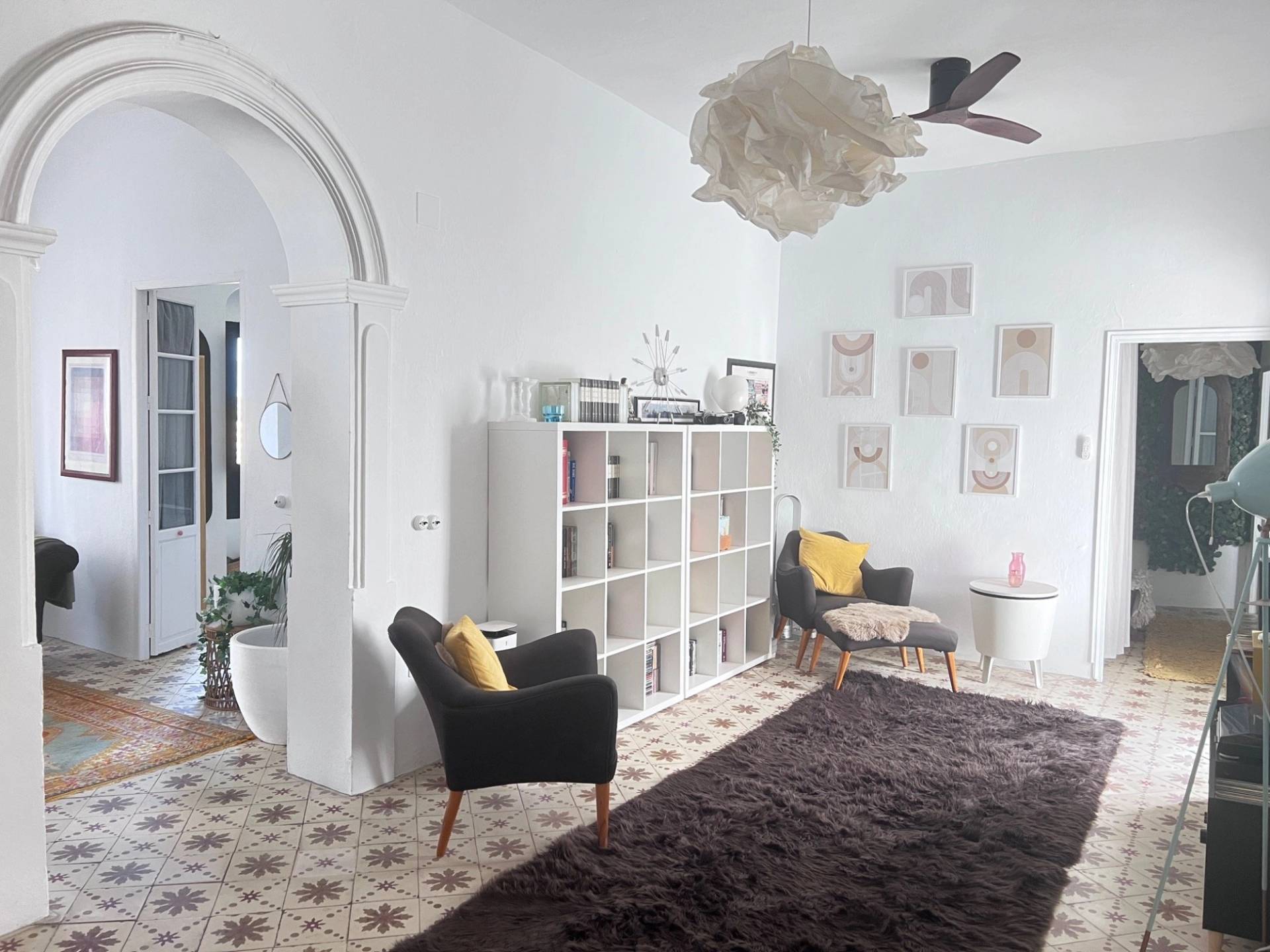 Spacious reception room shoot location in Jimena de la Frontera Cádiz from Love Locations, with high ceilings, patterned floor tiles, open shelving, and a grey armchair.