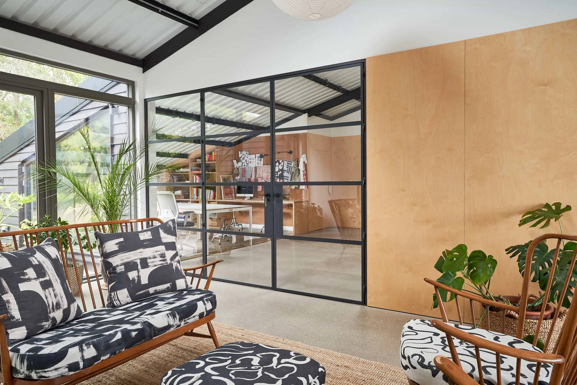 Lounge area featuring black steel framework, crittall glass walls, and monochrome patterned armchair seating, Love Locations IP30.