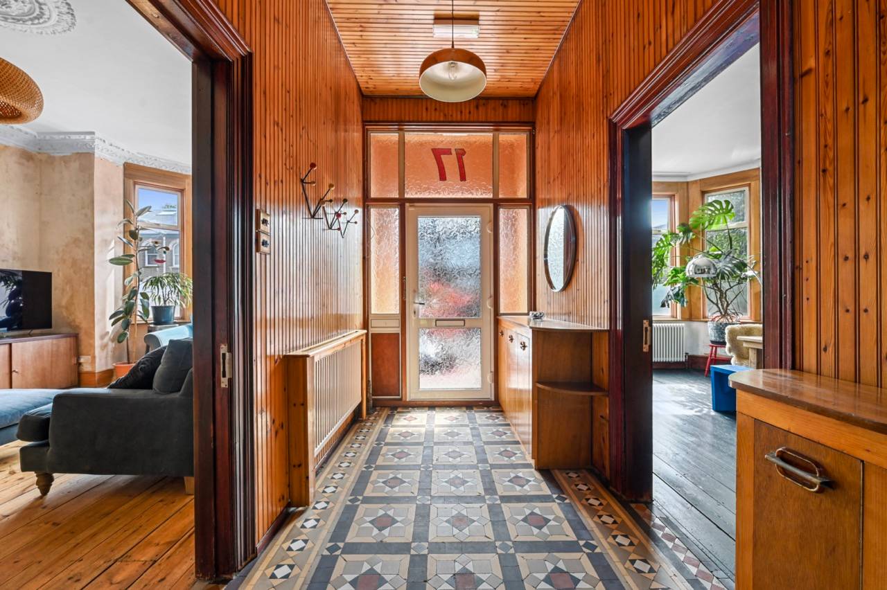 Victorian entrance hallway with pine wood panelling, ornate floor tile patterns, and a glass transom front door, Love Locations E7.