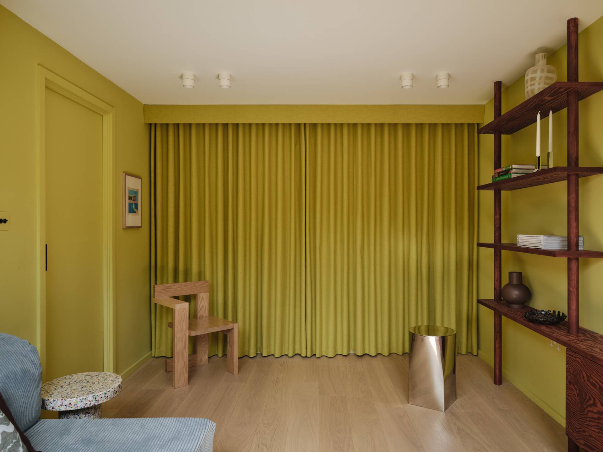 Love Locations bold chartreuse wall room Lewisham SE23: Atmospheric reading room with lime-chartreuse walls, integrated wooden floating shelves, and a sculptural wooden chair, perfect for music videos.