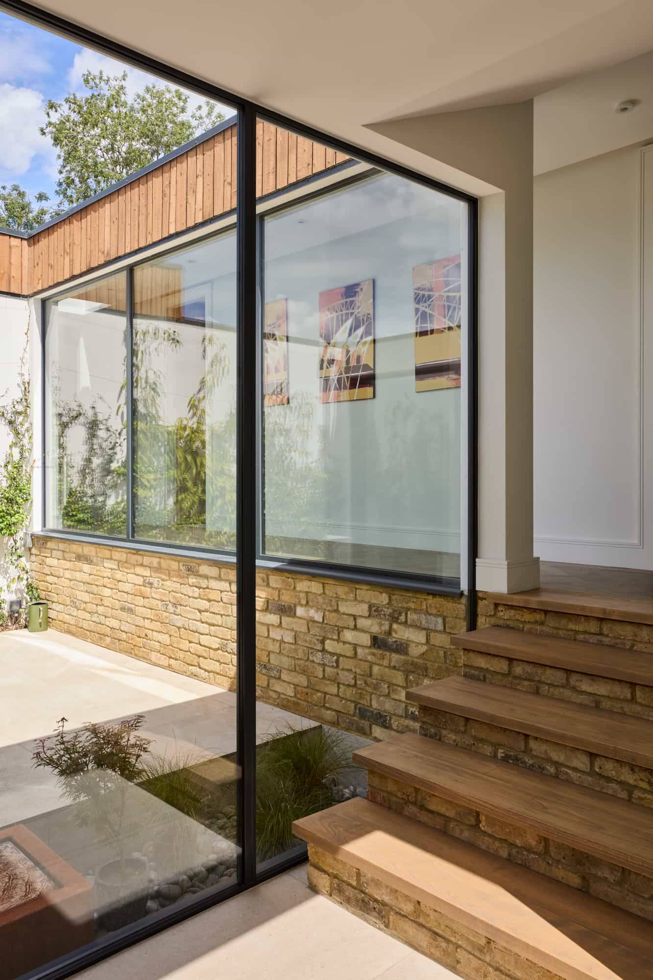 Glass walkway corridor framing views of a secluded interior stone courtyard garden, ideal for cinematic film scenes, Love Locations KT22.